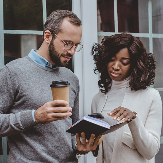 a couple in 30s or 40s looking at notes in a book together outside their home a couple in 30s or 40s looking at notes in a book together outside their home